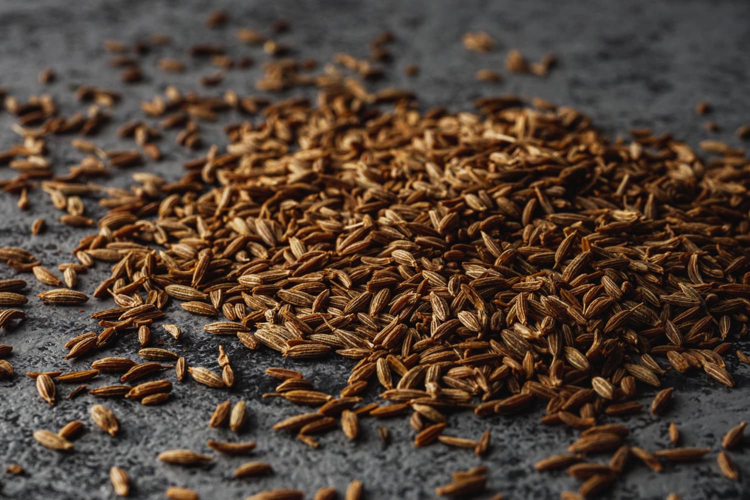 Un primer plano de las semillas y especias aromáticas del comino en un fondo rústico